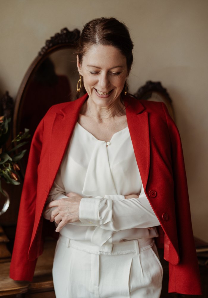 Gabriella Rist, Gründerin der GANESHASHALA® Trauma Fachakademie, im roten Blazer, lachend